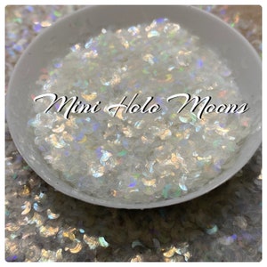 May include: A white bowl filled with iridescent, holographic, crescent-shaped glitter. The glitter is labeled "Mini Holo Moons".
