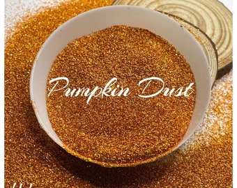 May include: A white bowl filled with orange glitter with a holographic finish. The glitter is labeled "Pumpkin Dust Holo".