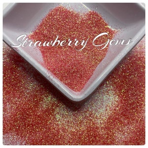 May include: A close-up of a small white dish filled with pink iridescent glitter. The glitter is labeled "Strawberry Gems".