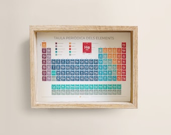 May include: A framed periodic table poster in Catalan, titled "Taula Periodica dels Elements". The poster features a colorful periodic table with the elements arranged in rows and columns. The poster is framed in a light wood frame.