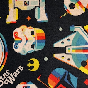 May include: A black fabric with a repeating pattern of Star Wars characters and spaceships. The characters and spaceships are outlined in rainbow colors. The text "Star Wars" is printed in white on the fabric.