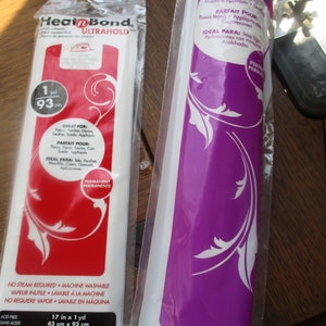 May include: Two rolls of fusible web, one red and one purple, with product information and instructions. The red roll is labeled "Heat'n Bond Ultrahold" and is 1 yard long. The purple roll is labeled "Great for Lightweight Fabrics" and is 4.8 meters long.