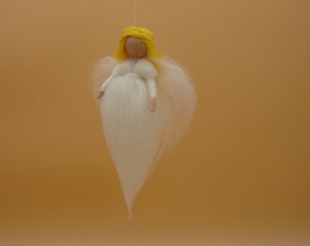 Puede incluir: Un adorno de ángel de fieltro blanco con cabello amarillo y un vestido blanco. El ángel está colgado de una cuerda.