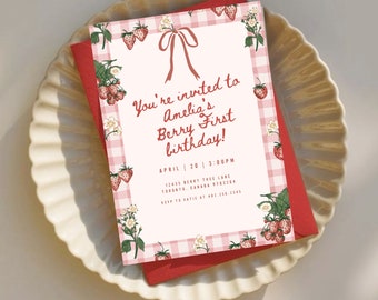 Peut inclure: Une invitation d'anniversaire sur le thème de la fraise. L'invitation présente un motif vichy rose et le texte "You're invited to Amelia's Berry First birthday!" avec des illustrations de fraises et de fleurs. Elle est posée sur une assiette blanche.