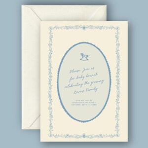 May include: Baby brunch invitation with a cream background and blue floral border. The invitation has an oval center with a rocking horse illustration and text that reads "Please Join us for baby brunch celebrating the growing Barns Family."