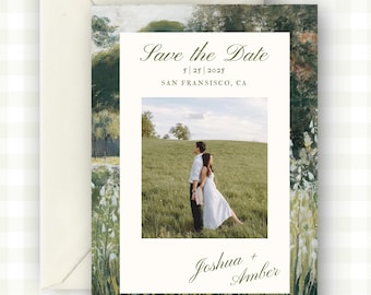 May include: Wedding invitation with a landscape painting border and a photo of a couple in a field. The text reads "Save the Date" with the date and location, and the names "Joshua + Amber". The invitation is in a cream-colored envelope.