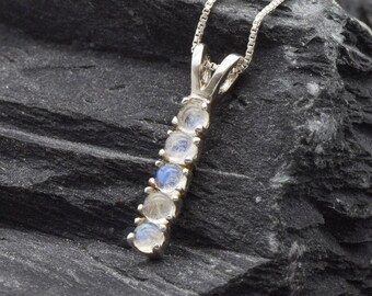 May include: A silver necklace with a pendant featuring six round moonstone gems in a row. The pendant is on a silver chain.