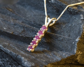 May include: A silver chain necklace with a pendant featuring a row of six round pink gemstones.