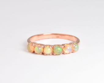 May include: A rose gold band ring with six opal gemstones set in a row.