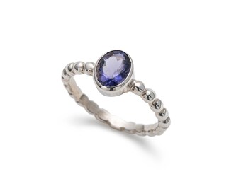 May include: A silver ring with a beaded band and a purple oval gemstone.