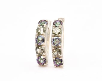 May include: A pair of silver hoop earrings with a row of iridescent green and purple gemstones.