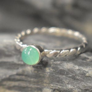May include: A silver ring with a twisted band and a light green gemstone.