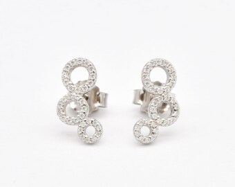 May include: A pair of silver earrings with three interlocking circles, each circle is adorned with small sparkling stones.