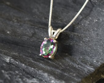 May include: A silver chain necklace with a pendant featuring a large oval-shaped iridescent gemstone. The gemstone displays a rainbow of colors, including green, pink, and blue.