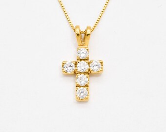 May include: A gold chain necklace with a small, gold cross pendant adorned with clear cubic zirconia stones.