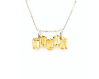 May include: A silver chain necklace with a pendant featuring five yellow gemstones in a row. The gemstones are rectangular and have a faceted cut.