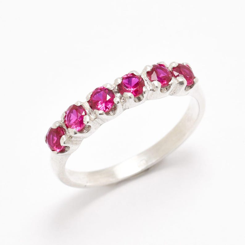 May include: A silver band ring with six pink gemstones set in a row.