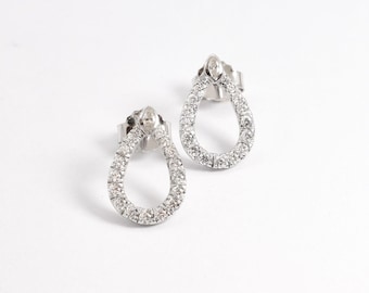 May include: A pair of silver teardrop shaped earrings with a single diamond at the top of each earring. The earrings are set with small diamonds around the perimeter.