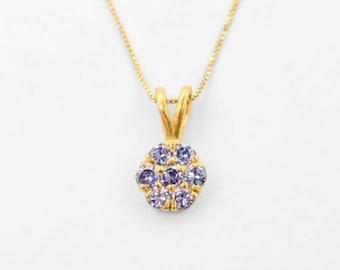 May include: A gold-colored necklace with a pendant featuring a cluster of light purple gemstones. The pendant is round and has a floral design. The chain is delicate and gold-colored, set against a white background.
