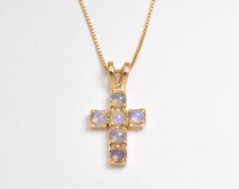 May include: A gold chain necklace with a cross pendant featuring five iridescent opal stones.