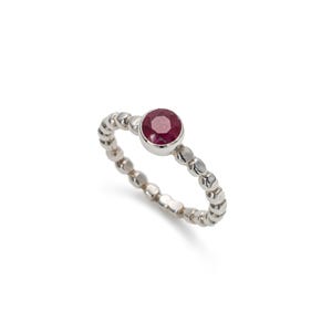May include: A silver ring with a red gemstone set in the centre. The ring is made of small beads.