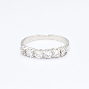 May include: A silver band ring with five clear round gemstones set in a row.