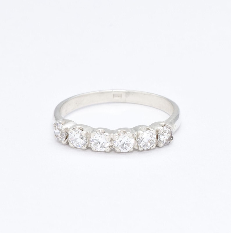 May include: A silver band ring with five clear round gemstones set in a row.