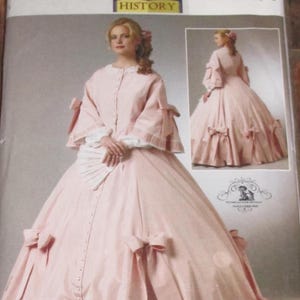 May include: A pink historical dress pattern by Butterick. The dress features a button-down bodice, bell sleeves, and a full skirt adorned with bows. The pattern includes a smaller image of the dress and the text "HISTORY".