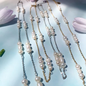 May include: Five delicate necklaces with pearl accents. The necklaces feature a silver chain with white pearls and a gold chain with white pearls.