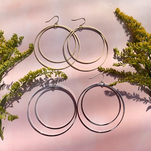 May include: Two pairs of hoop earrings, one pair is gold and the other is silver. Both pairs are double hoop earrings.