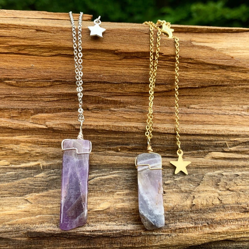 May include: Two amethyst crystal necklaces with gold and silver chains. The necklaces feature a star charm and a raw amethyst pendant.