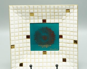 Puede incluir: Bandeja cuadrada de cerámica blanca con un diseño de mosaico dorado. La bandeja tiene un inserto azul turquesa con una corona dorada y un diseño floral. El texto "Fergus Brand" está impreso en dorado en el inserto azul turquesa.