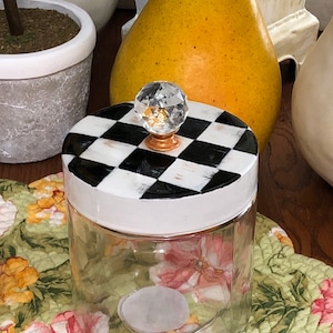 May include: A clear glass jar with a white lid and a black and white checkered design. The lid has a crystal knob.