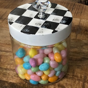 May include: A clear glass jar with a white lid and a black and white checkered design. The lid has a crystal knob. The jar is filled with pastel-colored jelly beans.