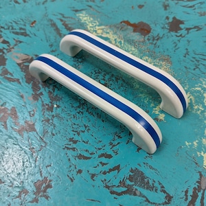 May include: Two white ceramic cabinet door pulls with blue stripes.