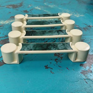May include: Five off-white drawer pulls with a green marble pattern. The pulls are stacked on top of each other.