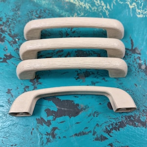 May include: Three off-white plastic cabinet door handles. The handles are stacked, with the top handle slightly offset from the bottom two handles.