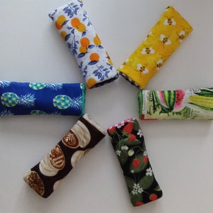 May include: Six fabric-covered ice packs with different patterns. The patterns include pineapples, oranges, bees, watermelon, corn, and pastries.