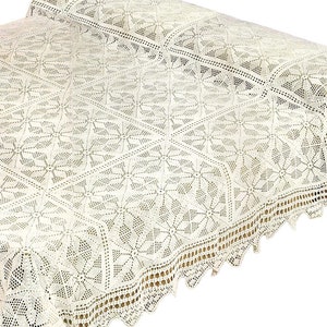 May include: A white crocheted bedspread with a delicate floral pattern and a scalloped edge.