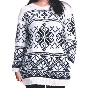 Könnte beinhalten: Weißer Pullover mit einem schwarz-weißen geometrischen Muster. Der Pullover hat lange Ärmel und einen Rundhalsausschnitt.