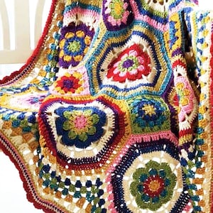 May include: A colorful crocheted blanket with a geometric pattern of flowers and hexagons. The blanket is made with a variety of bright colors, including red, orange, yellow, green, blue, and purple.
