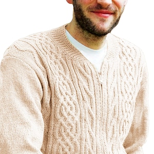 May include: A beige cable-knit sweater with a full zipper closure. The sweater features intricate cable patterns on the front and sleeves. The neckline is a V-shape, and the sweater appears to be made of a soft, warm material.