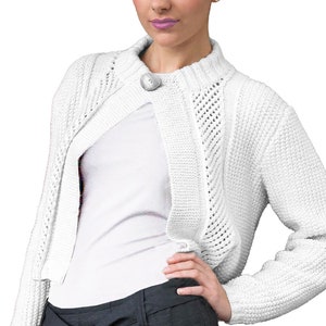 Puede incluir: Un cárdigan blanco de ganchillo con cierre de botón y una longitud ligeramente recortada. El cárdigan se lleva sobre una camiseta blanca y pantalones negros.