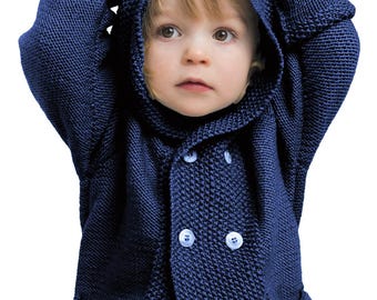 May include: A navy blue hooded sweater with white buttons. The sweater is knit and has a textured appearance. The child is wearing the sweater and has their hands on their head.