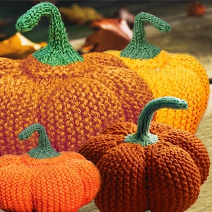 Peut inclure: Quatre citrouilles tricotées en orange et vert. Les citrouilles sont disposées sur une surface en bois avec des feuilles d'automne éparpillées autour d'elles.