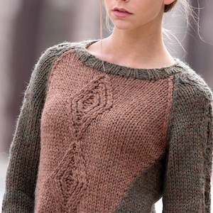 Könnte beinhalten: Ein brauner und grüner Strickpullover mit einem Rautenmuster auf der Vorderseite. Der Pullover hat einen runden Ausschnitt und lange Ärmel.