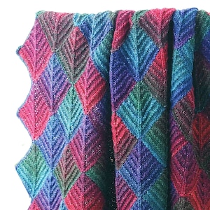 May include: A colorful knitted blanket with a diamond pattern in shades of purple, teal, green, and red.