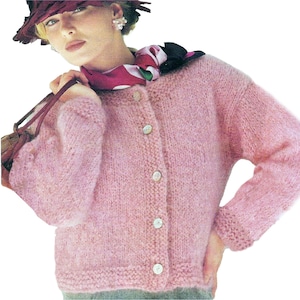 May include: A pale pink cardigan with a button-down front. The knitted sweater features a textured design and is fastened with five white buttons. The long sleeves have ribbed cuffs. This is a vintage garment, part of a clothing collection.