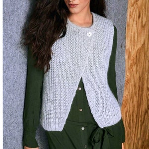 Könnte beinhalten: Eine hellgraue Strickweste mit Knopfleiste. Die Weste ist vorne offen und hat einen leicht V-förmigen Ausschnitt.