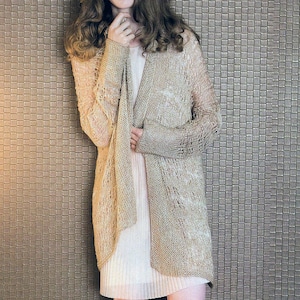 Puede incluir: Un cárdigan beige de abertura frontal con un delicado patrón de punto. El cárdigan está hecho de una tela suave y ligera y tiene un ajuste holgado.